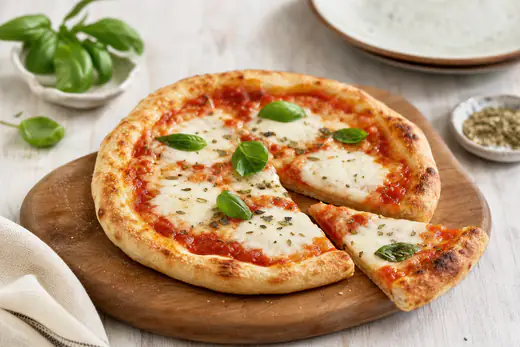 Pizzetta rotonda con mozzarella filante, salsa di pomodoro e foglie di basilico fresco, appoggiata su un tagliere di legno