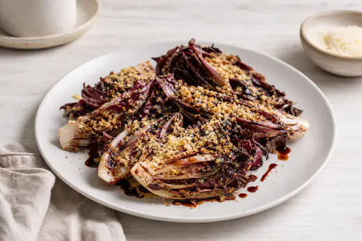 Spicchi di radicchio rosso caramellati con bordi scuri e croccanti e una gratinatura dorata di parmigiano, in un piatto bianco